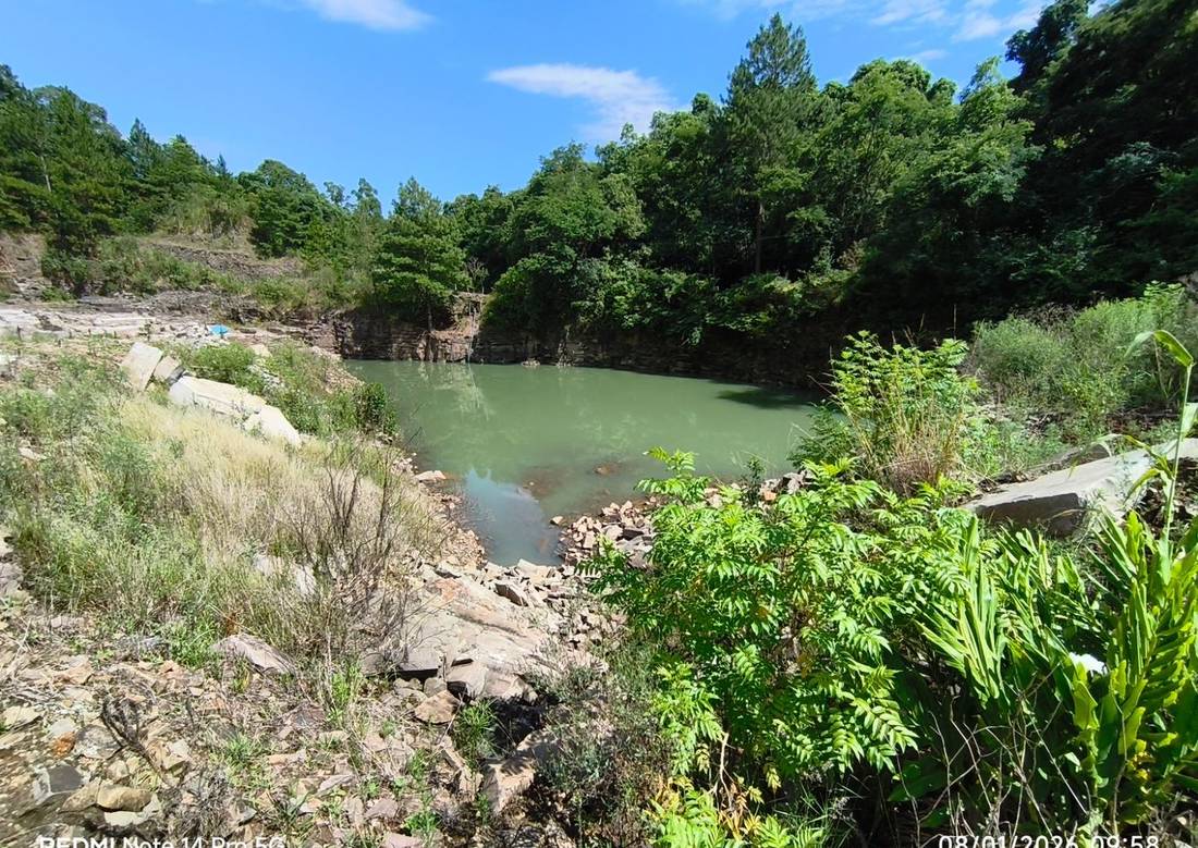 Lago natural formado em área de cava de basalto recuperada, cercado por vegetação nativa densa