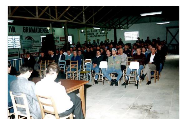 Reunião social da categoria de basalteiros em galpão, com grande público sentado