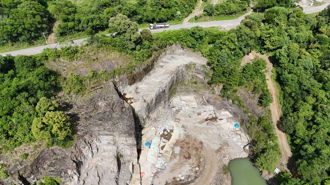 Vista aérea de drone de uma cava de basalto em Nova Prata, RS, com estrada de acesso e área de mata nativa ao redor